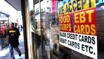 A sign in a New York City market window advertises the acceptance of food stamps.