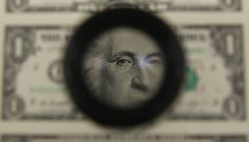 A magnifying glass is used to inspect newly printed one dollar bills at the Bureau of Engraving