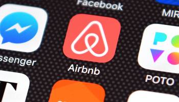 The Airbnb app logo is displayed on an iPhone.