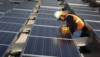 A worker installs a solar panel on top of a government building in Lakewood, Colorado in 2010.