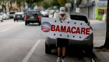 A man holds a sign directing people to sign up for Obamacare.