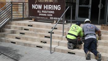 A "Now Hiring" sign on the steps of a business.