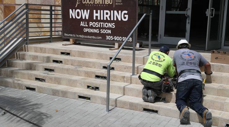 A "Now Hiring" sign on the steps of a business.
