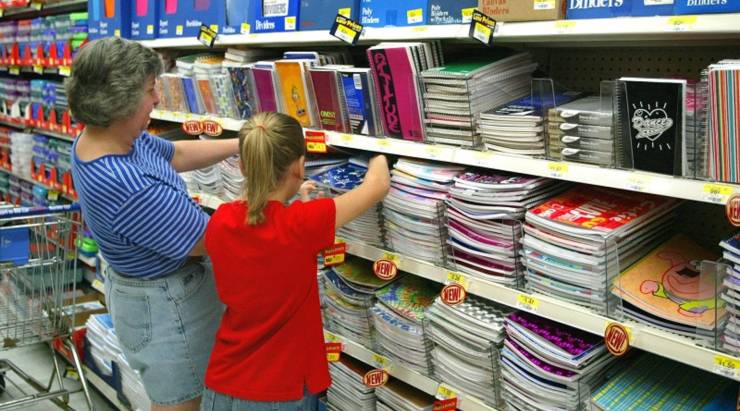 A woman and girl peruse notebooks and school supplies at a store.