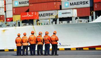 Workers stand in line next to a container ship at a port in Qingdao in China's eastern Shandong province earlier this month.