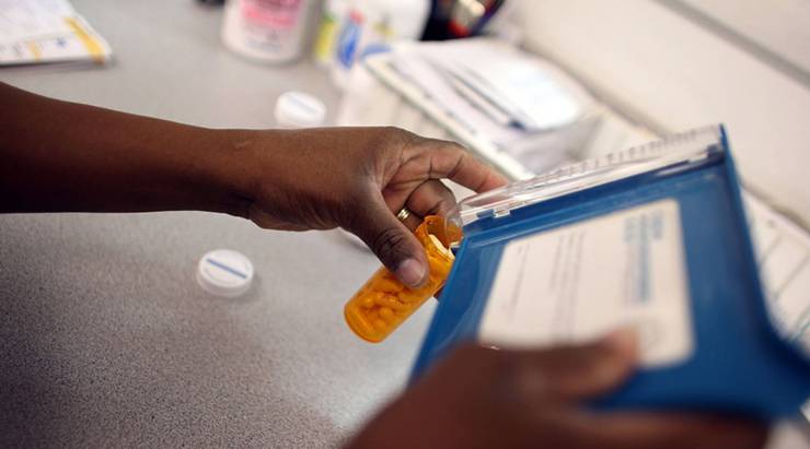 A pharmacy technician counts out a prescription of antibiotic pills.