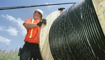 A reel tender helps install fiber-optic cable onto telephone poles in Louisville, Colorado, in 2001.
