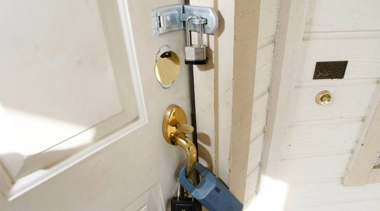 A padlock and real estate agent key lock boxes are seen on a front door
