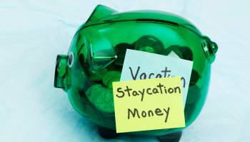 A piggy bank with a sticky note that reads "Staycation Money."