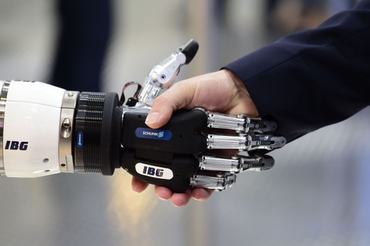A person shakes hand with a robot.