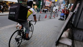 A man delivers a food order by bicycle for Uber Eats in Tokyo's Shibuya shopping district in 2018.