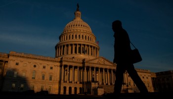 A person walks outside the Capitol Building as the sun rises over Washington, D.C.