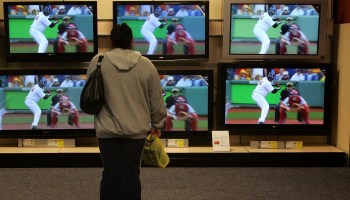 A woman stands in front of televisions for sale.