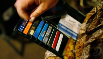 A woman looks at many different credit cards in her wallet.