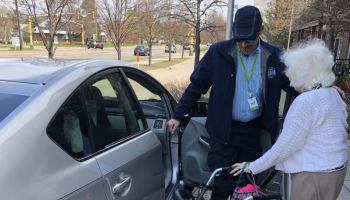 Mobility4All driver Peter Sarafolean helps rider Lois Lundemo get in the car so she can go shop for fabrics.