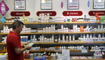A man looks at a pill bottle in a store.