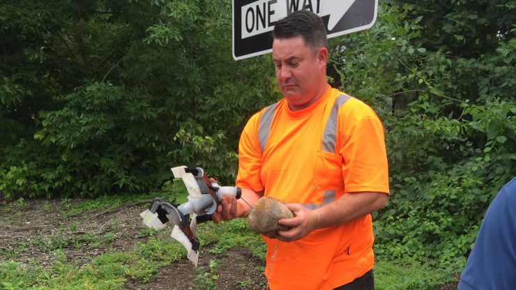 A utility worker retrieves Scout, a leak-seeking robot, after it emerges from an open fire hydrant.