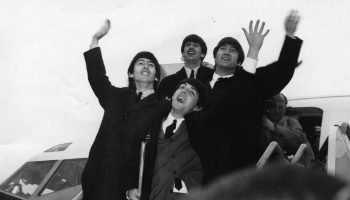 25th February 1964: The Beatles on the steps of an airplane, waving to their fans.