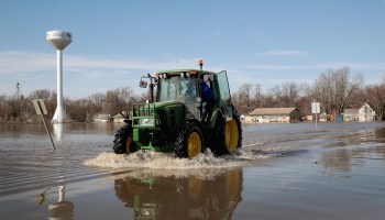 A tractor plows through the flooded streets of Craig, Missouri.
