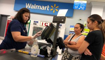 A Walmart cashier rings up purchases as customers look on.