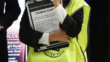 An airport official holds information for Thomas Cook passengers at Manchester Airport in northern England on Monday after the company collapsed.