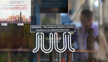 A neon sign advertising Juul e-cigarettes is displayed in a window of a tobacco store in June in San Francisco.