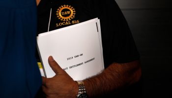 A United Auto Workers member carries a copy of the contract settlement agreement outside of a UAW GM Council meeting in Detroit on Thursday.