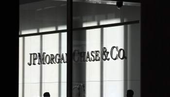 People pass a sign for JPMorgan Chase & Co. at it's headquarters in Manhattan.