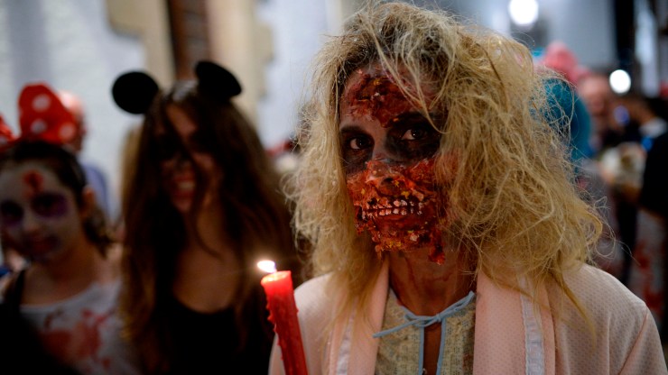 Preparing for the zombie apocalypse can prepare you for all kinds of disasters. Above, a woman in zombie makeup holds a candle while participating in a Zombie Walk in Sitges, Spain, in 2018.
