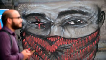 A man walks by graffiti depicting a one-eyed demonstrator -in reference to those injured in recent clashes with police