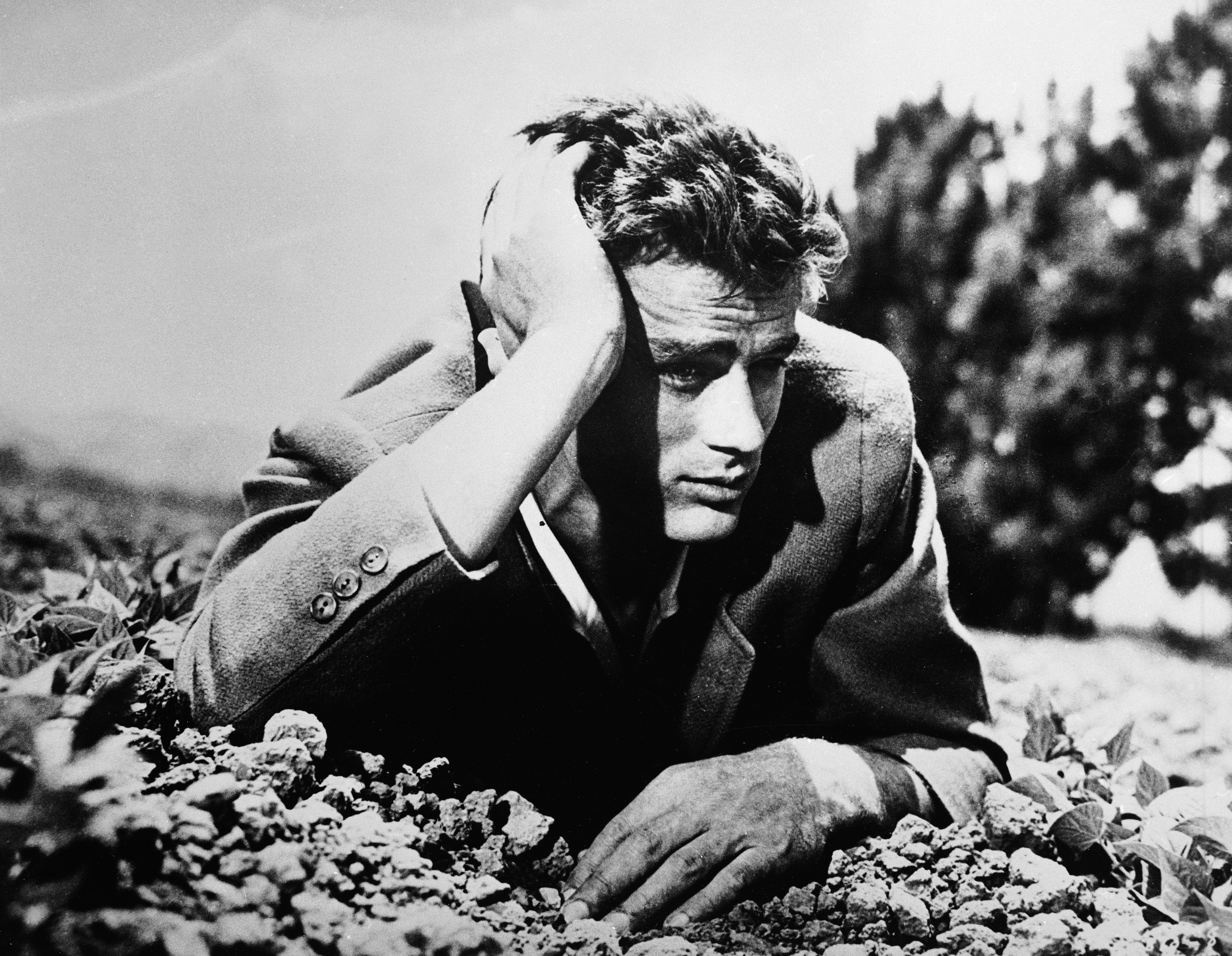American actor James Dean (1931 - 1955) lies in the dirt with his head leaning on his hand, 1950s.