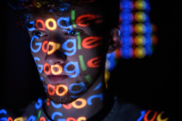 The Google logo is projected onto a man in this photo illustration.