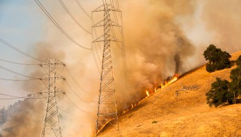 A backfire set by firefighters burns behind PG&E power lines as part of efforts to battle the Kincade fire in Healdsburg, California, on Oct. 26.