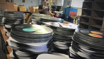 An Archer Record Pressing employee takes a lunch break amidst stacks of freshly pressed vinyl.