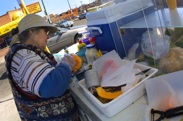Sidewalk street vendor Maria Rodriguez prepares a melon for a customer March 21, 2001 in Chicago's mainly Hispanic Little Village neighborhood. In his book, "Barrio America," A.K. Sandoval-Strausz makes the case that Latino Immigrants to neighborhoods like Little Village helped save America's cities.