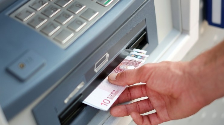 A man takes out Euros from an ATM in Carquefou, France