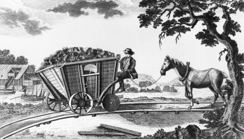 A Newcastle coal wagon of 1773 from "A Picture History of Railways" by C. Hamilton Ellis, showing a filled wagon with flanged wheels and a horse following behind on a down-gradient railway line.