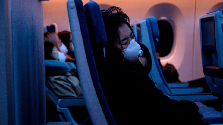 Passengers wearing protective face masks sleep on their flight to Shanghai on Feb. 4.