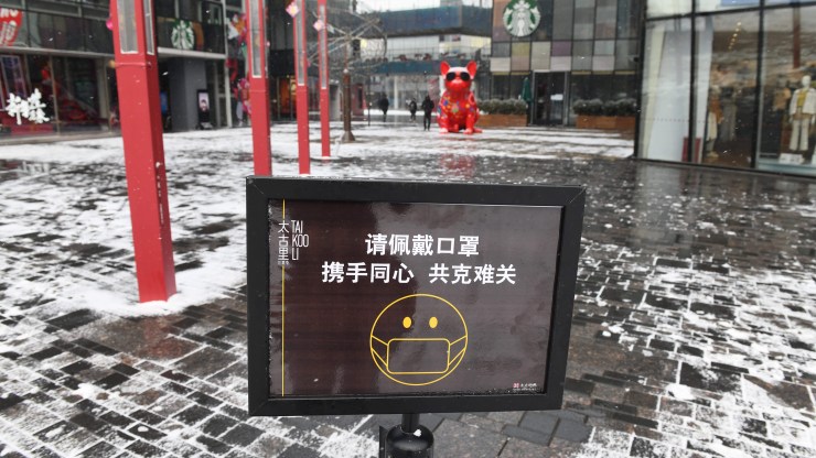 A sign urges visitors to wear face masks at the entrance to an empty shopping mall in Beijing on Feb. 5, 2020.