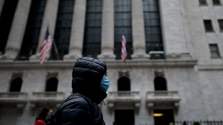 A woman in a facial mask walks by the New York Stock Exchange on Feb. 3.