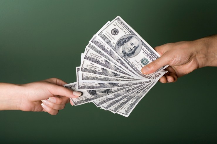 A hand holding $100 bills.