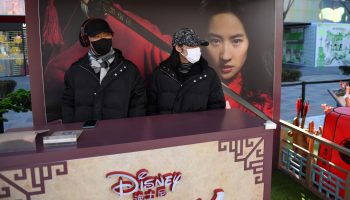 Two people wearing face masks work a promotional stand for the Disney movie "Mulan" in an almost empty shopping mall in Beijing.