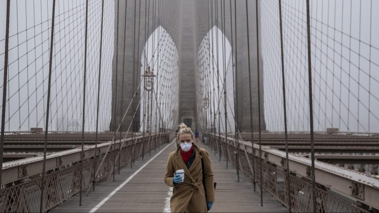 A woman wearing a mask walks the Brooklyn Bridge in the midst of the coronavirus (COVID-19) outbreak on March 20, 2020 in New York City.
