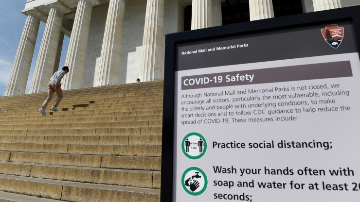 A teenager passes a sign with information about coronavirus safety measures at the Lincoln Memorial in Washington, D.C., on March 27.
