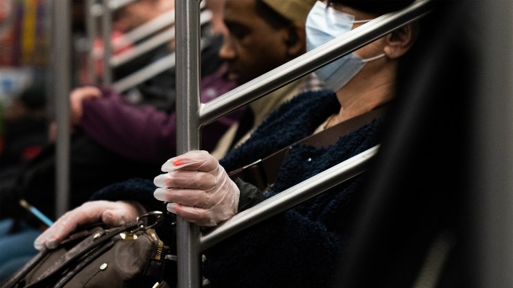 A woman wearing a protective mask and latex gloves rides a subway on March 9, 2020 in New York City.