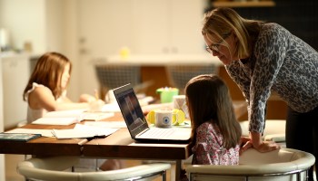 A mom in Marin County, California, helps her daughters with schoolwork at the kitchen table on March 18