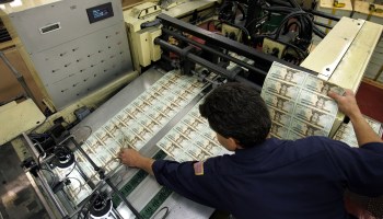 A worker checks money being printed at the Department of the Treasury Bureau of Engraving and Printing in Washington, D.C.