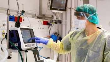 A doctor wearing personal protective gear checks a ventilator on March 16