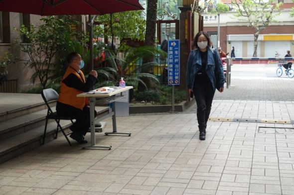 A security guard is stationed at an entrance to check people for fever before entering though in recent weeks the measures have relaxed. (Charles Zhang/Marketplace)