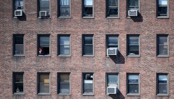 A resident looks out an apartment window in New York. For many, the rent is due tomorrow.
